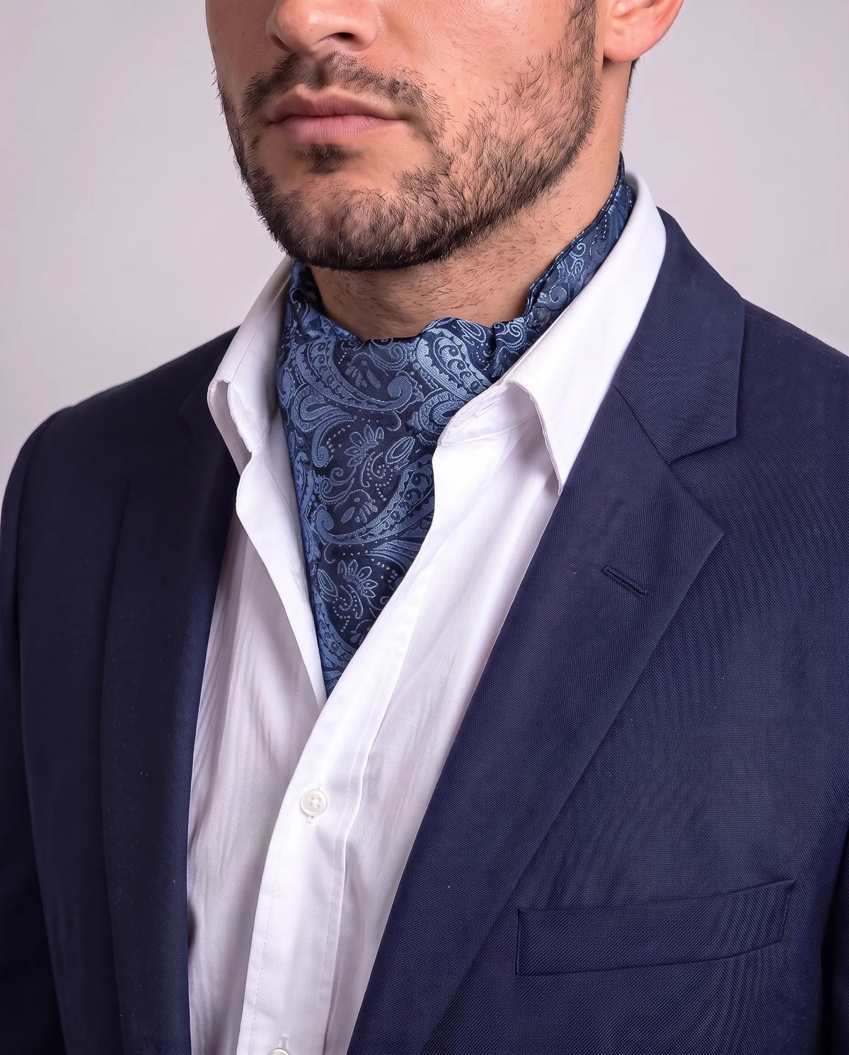 Mann i mørk dressjakke og hvit skjorte med marineblå paisley ascot, modell Nice