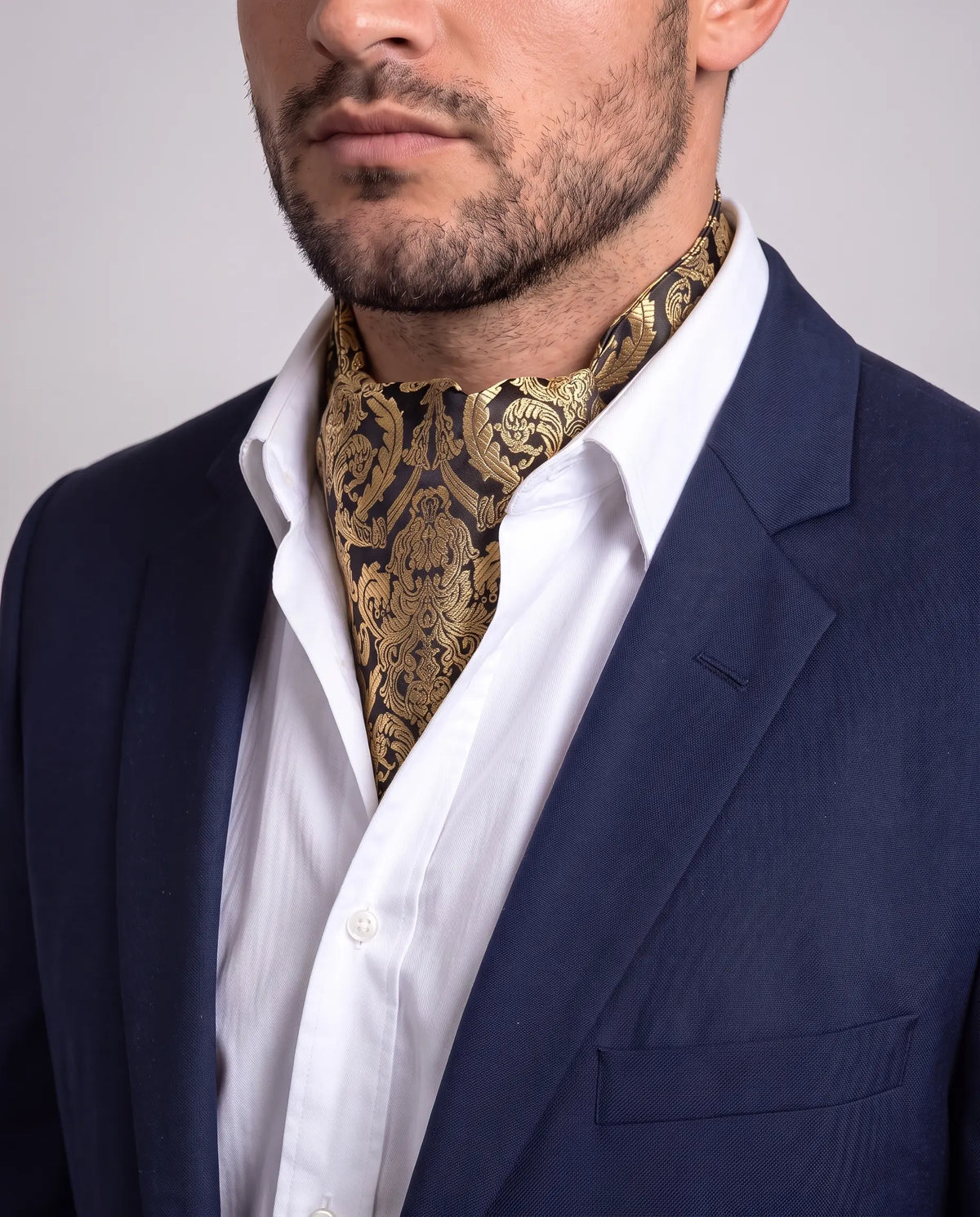 Mann i mørk dressjakke og hvit skjorte med sort og gull barokk ascot, modell Wien